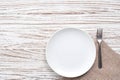 Empty plate napkin fork silverware white wooden table background Royalty Free Stock Photo