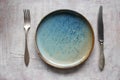 Empty plate with silverware knife and fork on a light background.