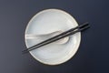 Empty plate, spoon and chopsticks on black table in asian restaurant, close up Royalty Free Stock Photo