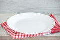 Empty plate on tablecloth or napkin on wooden table over cement background Royalty Free Stock Photo