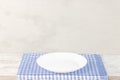 Empty plate on tablecloth or napkin on wooden table over cement background Royalty Free Stock Photo