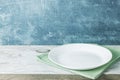 Empty plate on tablecloth on wooden table over grunge blue Royalty Free Stock Photo