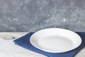 Empty plate on tablecloth on wooden table over grunge blue background Royalty Free Stock Photo