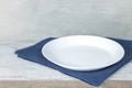 Empty plate on tablecloth on wooden table over grunge blue background Royalty Free Stock Photo