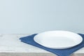 Empty plate on tablecloth on wooden table over grunge blue background Royalty Free Stock Photo