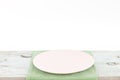 Empty plate on tablecloth on wooden table over grunge gray background Royalty Free Stock Photo