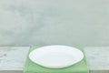 Empty plate on tablecloth on wooden table over grunge gray background Royalty Free Stock Photo