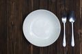 Empty plate or white dish with spoon and fork on wooden table ba Royalty Free Stock Photo