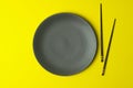 Empty plate on a yellow background. Empty plate for asian and chinese food and cuisine with chinese chopsticks Royalty Free Stock Photo