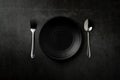 Empty plates, spoons and forks Black kitchen utensils set on a stone table. Flat top view with copy space Royalty Free Stock Photo