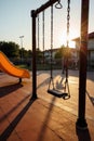 Empty playground at dawn, sunlight casting long shadows on swings and slides. An empty playground at dawn, with long shadows cast Royalty Free Stock Photo