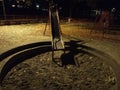 An empty playground with a red metal slide at night and creepy atmosphere