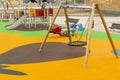 Empty playground with swings and safe rides with anti-traumatic bright rubber crumb coating Royalty Free Stock Photo