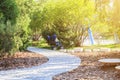 empty pram stands near modern playground with modern minimalist path of round wooden plates in Park leading on ground mulched bark