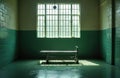 Empty prison cell with metal bed on wheels. Sunlight streams through large barred window casting shadows. Abandoned institutional Royalty Free Stock Photo