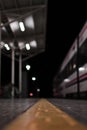 Empty rail road station at night. The train is going on the tracks Royalty Free Stock Photo