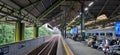 Empty railroad tracks next to visitors waiting in the waiting room at noon at Gambir train station, Jakarta.