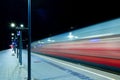 Empty railway station platform with passing train at night. Royalty Free Stock Photo