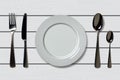 Empty realistic plate with spoon, knife and fork on a white wooden background. Cutlery on a wood table Royalty Free Stock Photo