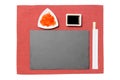 Empty rectangular black slate plate with chopsticks for sushi, ginger and soy sauce on red napkin background. Top view with copy Royalty Free Stock Photo