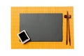 Empty rectangular black slate plate with chopsticks for sushi and soy sauce on yellow bamboo mat background. Top view with copy Royalty Free Stock Photo