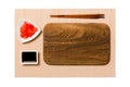 Empty rectangular brown wooden plate with chopsticks for sushi, ginger and soy sauce on brown sushi mat background. Top view with Royalty Free Stock Photo