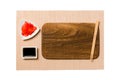 Empty rectangular brown wooden plate with chopsticks for sushi, ginger and soy sauce on brown sushi mat background. Top view with Royalty Free Stock Photo