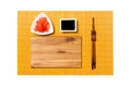 Empty rectangular brown wooden plate with chopsticks for sushi, ginger and soy sauce on yellow bamboo mat background. Top view Royalty Free Stock Photo