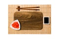 Empty rectangular brown wooden plate with chopsticks for sushi, ginger and soy sauce on yellow bamboo mat background. Top view Royalty Free Stock Photo