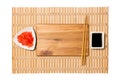 Empty rectangular brown wooden plate with chopsticks for sushi and soy sauce, ginger on yellow bamboo mat background. Top view Royalty Free Stock Photo