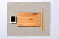 Empty rectangular brown wooden plate with chopsticks for sushi and soy sauce on grey napkin background. Top view with copy space Royalty Free Stock Photo