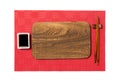 Empty rectangular brown wooden plate with chopsticks for sushi and soy sauce on red mat sushi background. Top view with copy space Royalty Free Stock Photo