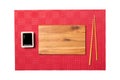 Empty rectangular brown wooden plate with chopsticks for sushi and soy sauce on red mat sushi background. Top view with copy space Royalty Free Stock Photo