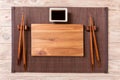 Empty rectangular wooden plate for sushi with sauce and chopsticks on wooden table, top view Royalty Free Stock Photo