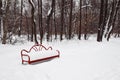 Empty red bench covered with snow in a winter city park Royalty Free Stock Photo