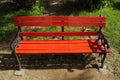 An empty red bench in a garden with green back drop.. Royalty Free Stock Photo