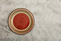 Empty red ceramic dish plate with spiral pattern on gray background. Top view with copy space. Royalty Free Stock Photo