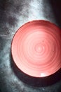 Empty red ceramic plate with spiral pattern over textured rustic concrete background Royalty Free Stock Photo