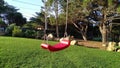 Empty red children`s swing on a background of green grass in the garden