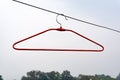 An empty red cloth hanger on the outside with trees in the background Royalty Free Stock Photo