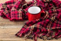 empty red cup and cozy plaid on wooden background