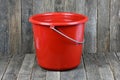 Empty red plastic household bucket on dark wood background Royalty Free Stock Photo