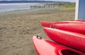 Empty red plastic recreational kayaks for rent or hire, stored on sandy beach after hours on a rainy day. Crescent Beach, Surrey, Royalty Free Stock Photo