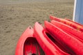 Empty red plastic recreational kayaks for rent or hire, stored on sandy beach after hours on a rainy day. Crescent Beach, Surrey, Royalty Free Stock Photo