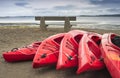 Empty red plastic recreational kayaks for rent or hire, stored on sandy beach after hours on a rainy day. Crescent Beach, Surrey, Royalty Free Stock Photo