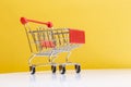 Empty red shopping cart on yellow background. close-up.