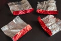 Empty red and silver candy wrappers on a black background. Crump Royalty Free Stock Photo