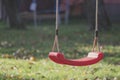 Empty red swing on children playground in the park in autumn season. Missing child. Royalty Free Stock Photo