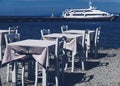 Empty restaurant by the Aegean sea and cruise boat, travel and nature Royalty Free Stock Photo