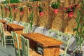 Empty restaurant outdoor seating area with wooden chairs and tables, decorated with flowers on red pots around Royalty Free Stock Photo